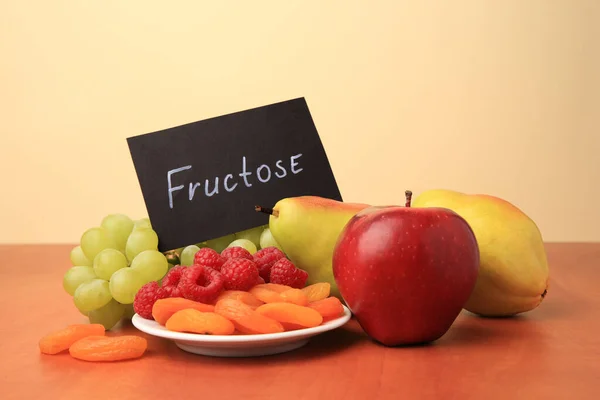 stock image Card with word Fructose, delicious ripe fruits, raspberries and dried apricots on wooden table