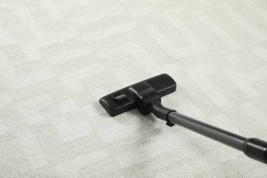 Modern elektrik süpürgesiyle beyaz halıdaki kiri temizliyorum.