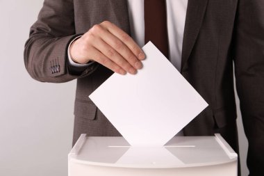 Adam oyunu açık gri arka planda sandığa koyuyor, yakın plan.