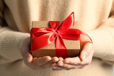 Elinde kırmızı fiyonklu hediye kutusu olan kadın, yakın plan.
