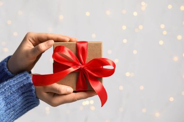 Kırmızı kurdeleli hediye kutusunu bulanık ışık, yakın çekim ve mesaj için alan kadınlara karşı tutan kadın. Bokeh etkisi