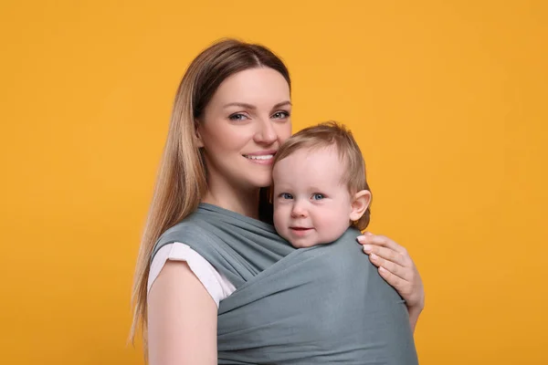 Madre Sosteniendo Hijo Una Envoltura Bebé Sobre Fondo Naranja —  Fotos de Stock