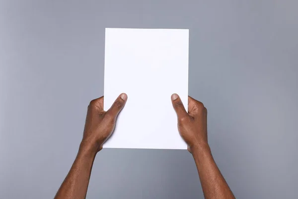 African American Man Holding Sheet Paper Grey Background Closeup Mockup — Stok fotoğraf