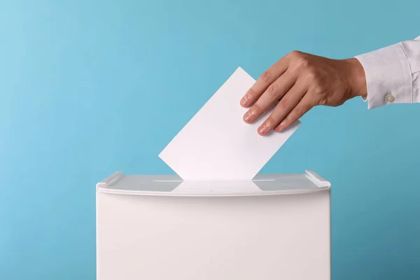 男子把他的选票放在投票箱浅蓝色背景 — 图库照片