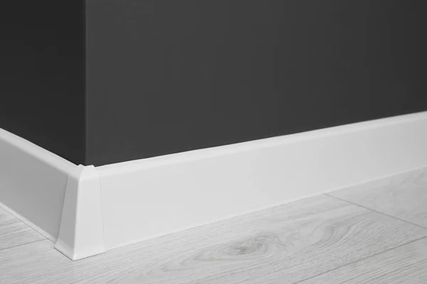 Witte Plint Met Connector Gelamineerde Vloer Nabij Zwarte Wand Binnen — Stockfoto