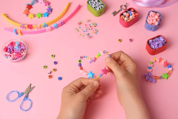 위에서 내려다보는 분홍색 배경에서 장신구와 물품을 만드는 아이들 손으로 액세서리 — 스톡 사진