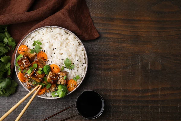 stock image Delicious rice with fried tofu, broccoli and carrots served on wooden table, flat lay. Space for text