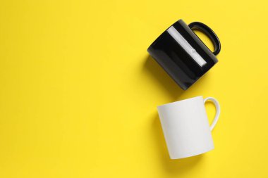 Sarı arka planda siyah beyaz seramik kupalar, düz. Metin için boşluk