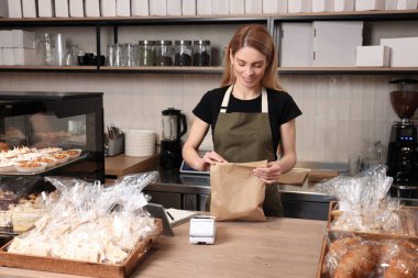 Pastanedeki kasiyer masasında kese kağıdıyla mutlu satıcı