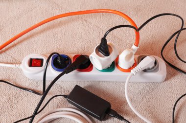 Beyaz halıda farklı elektrik prizleri olan elektrik şeridi.