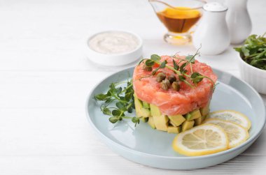 Avokado, limon, kapari ve beyaz ahşap masada mikro yeşillik ile lezzetli somon tartar. Metin için boşluk