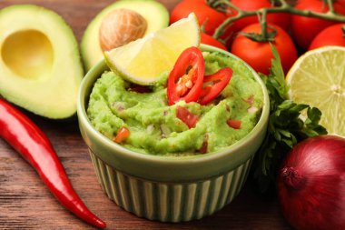 Bir kase lezzetli guacamole ve ahşap masa malzemeleri, yakın plan.