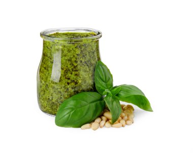 Cam kavanozda lezzetli pesto sosu, beyaz arka planda çam fıstığı ve fesleğen.