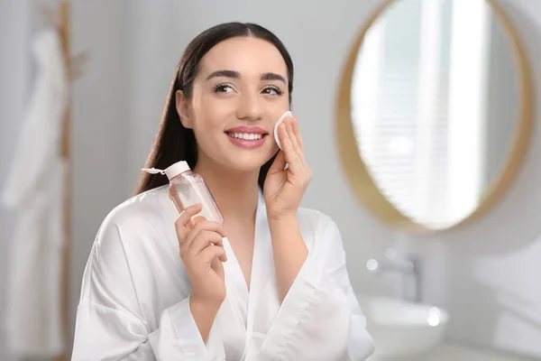 stock image Beautiful woman removing makeup with cotton pad indoors