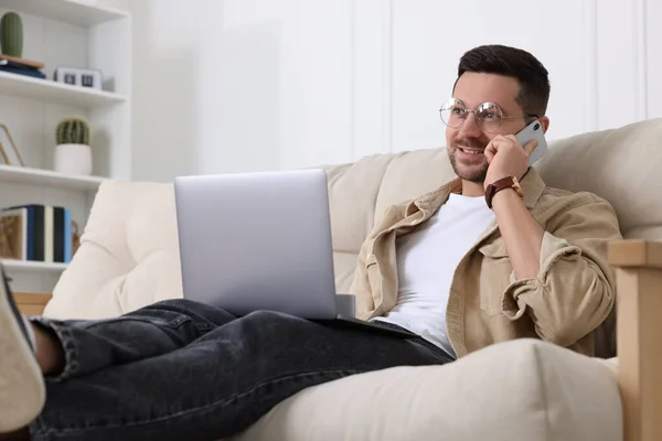 Evdeki Kanepede Dizüstü Bilgisayarla Çalışırken Telefonda Konuşan Mutlu Bir Adam — Stok fotoğraf