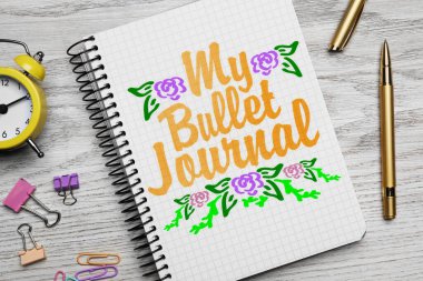 Verimliliğini arttır. Sözcüklerle dolu bir defter. Kurşun günlüğüm, çizilmiş çiçekler, kırtasiye ve çalar saatim beyaz ahşap masa üzerinde, düz bir şekilde yatıyordu.