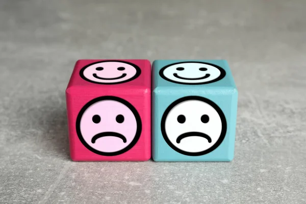Complaint. Pink and light blue wooden cubes with sad and happy on different sides