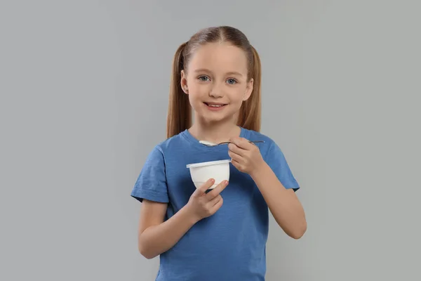 Nettes Kleines Mädchen Mit Leckerem Joghurt Auf Grauem Hintergrund — Stockfoto