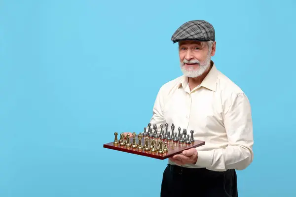 明るい青の背景にチェス盤とゲームの作品を持つ男 テキストのスペース — ストック写真