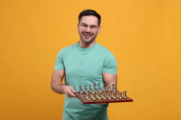 Χαμογελώντας Άνθρωπος Κρατώντας Σκακιέρα Κομμάτια Του Παιχνιδιού Πορτοκαλί Φόντο — Φωτογραφία Αρχείου