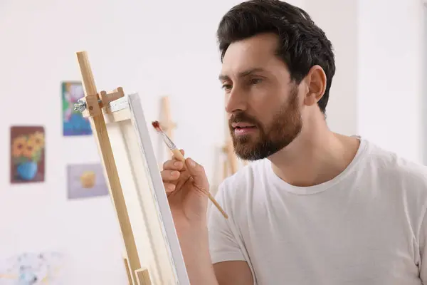 남자는 스튜디오에서 그림을 그립니다 용하여 캔버스를 붙들고 — 스톡 사진