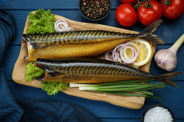 Delicious smoked mackerels and products on blue wooden table, flat lay