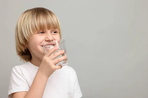 Niño Feliz Bebiendo Agua Dulce Sobre Fondo Gris Claro Espacio — Foto de Stock