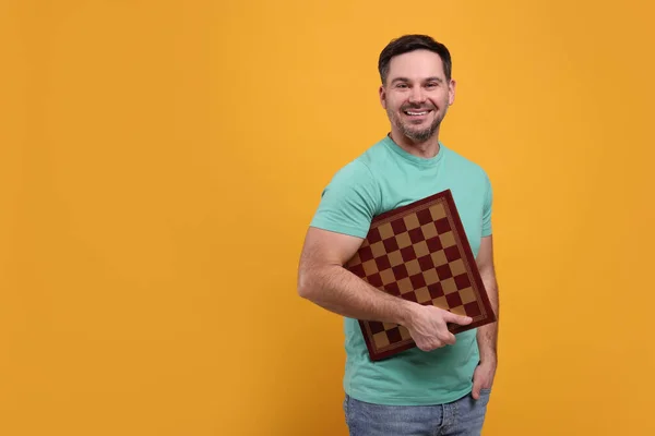 Χαμογελώντας Άνθρωπος Κρατώντας Σκακιέρα Πορτοκαλί Φόντο Χώρος Για Κείμενο — Φωτογραφία Αρχείου