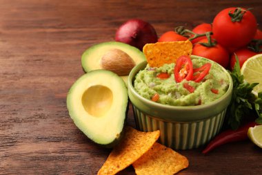 Bir kase lezzetli guacamole, cips ve ahşap masa malzemeleri, yakın plan. Metin için boşluk
