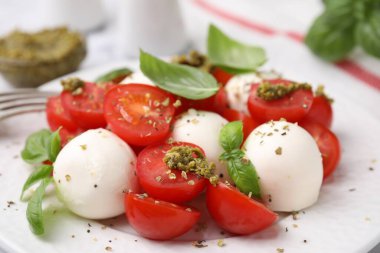 Domatesli Caprese salatası, mozzarella topları ve tabakta fesleğen, yakın plan.