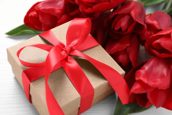 Schöne Geschenkschachtel Mit Schleife Und Roten Tulpenblumen Auf Weißem Tisch — Stockfoto