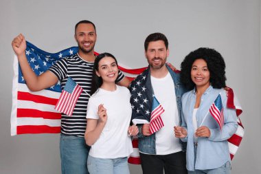 4 Temmuz - ABD 'nin Bağımsızlık Günü. Gri arka planda Amerikan bayrakları olan mutlu arkadaşlar