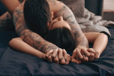 Tutkulu çift yatakta sevişiyor, ellerine odaklanıyor.