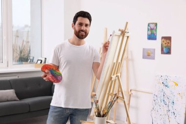 Stüdyoda resim yapan adam. Tuvali tutmak için resim sehpası kullanılıyor