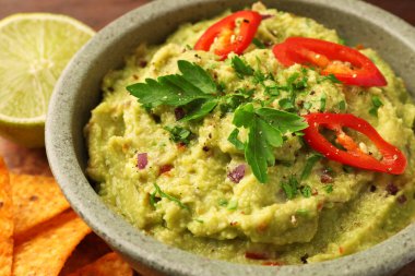 Bir kase lezzetli guacamole, limon ve tortilla cipsi, yakın plan.