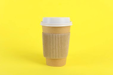 Sarı arka planda plastik kapaklı kağıt bardak. Kahve hazır.