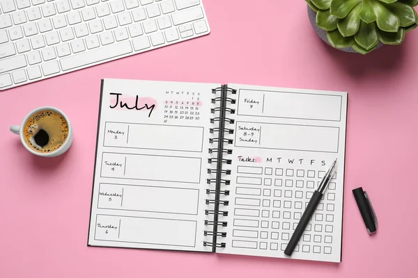 Self organization with bullet journal. Notebook with calendar, empty planning lists, pen and coffee on pink table, flat lay