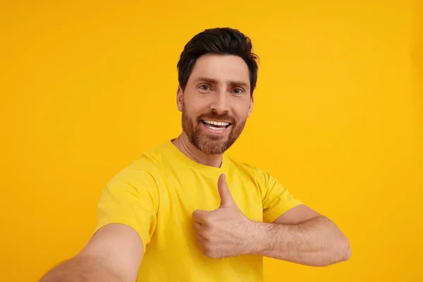 Uśmiechnięty Mężczyzna Robi Selfie Pokazuje Kciuki Żółtym Tle — Zdjęcie stockowe