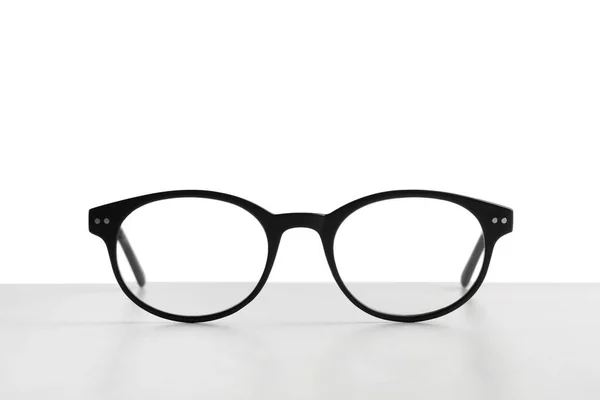 Óculos Elegantes Com Moldura Preta Mesa Contra Fundo Branco — Fotografia de Stock