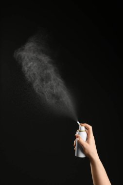 Burun tıkanıklığı. Siyah arka planda şişeden ilaç sıkan kadın, yakın plan.