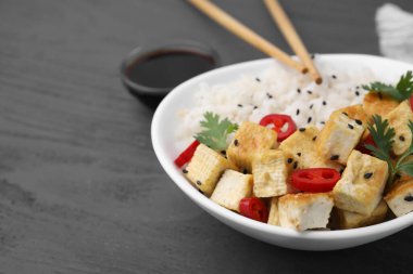 Bir kase pilav, kızarmış tofu, biber ve maydanozlu gri ahşap masa, yakın plan. Metin için boşluk