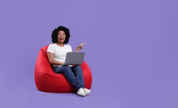 Ευτυχισμένη Νεαρή Γυναίκα Φορητό Υπολογιστή Κάθεται Καρέκλα Beanbag Μωβ Φόντο — Φωτογραφία Αρχείου