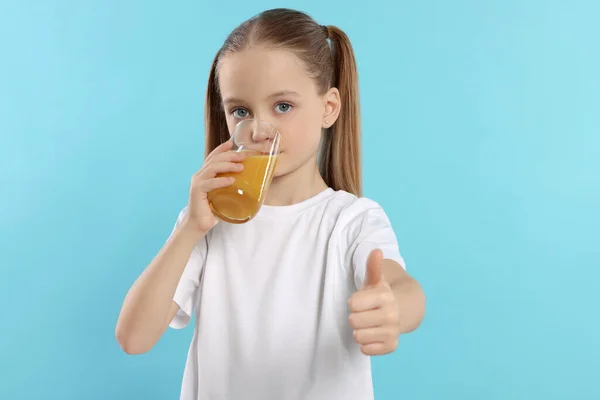Dziewczynka Pije Świeży Sok Pokazuje Kciuki Jasnoniebieskim Tle — Zdjęcie stockowe