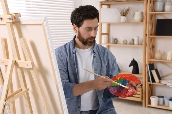 Człowiek Malowaniem Pędzlem Paletą Studio Używając Sztalugi Trzymania Płótna — Zdjęcie stockowe