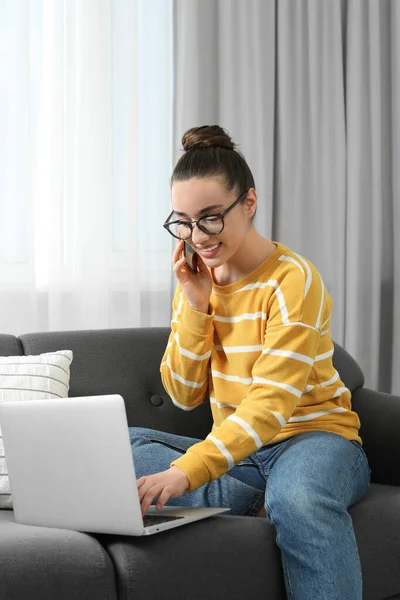 家庭工作场所在房间里一边用笔记本电脑一边用智能手机聊天的快乐女人 — 图库照片