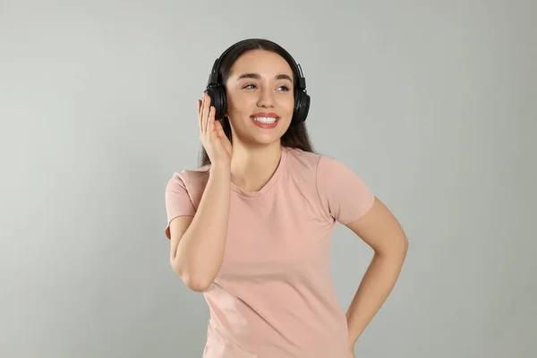Glückliche Frau Mit Kopfhörern Die Musik Auf Grauem Hintergrund Hört — Stockfoto