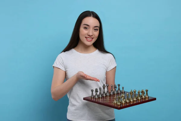 Счастливая Женщина Показывает Шахматную Доску Игровыми Фигурами Светло Голубом Фоне — стоковое фото