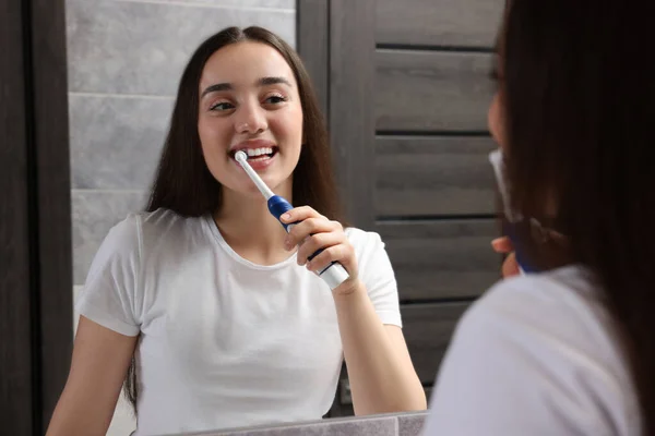 Mladá Žena Čištění Zubů Elektrickým Zubním Kartáčkem Blízkosti Zrcadla Koupelně — Stock fotografie