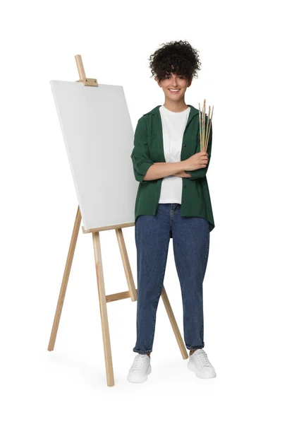 年轻女子拿着画笔靠近画架 画布衬着白色背景 — 图库照片