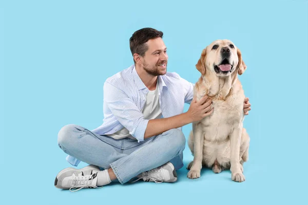 ラブラドール レトリバーの可愛い犬と一緒に ライトブルーの背景で抱き合っている男 可愛いペット — ストック写真